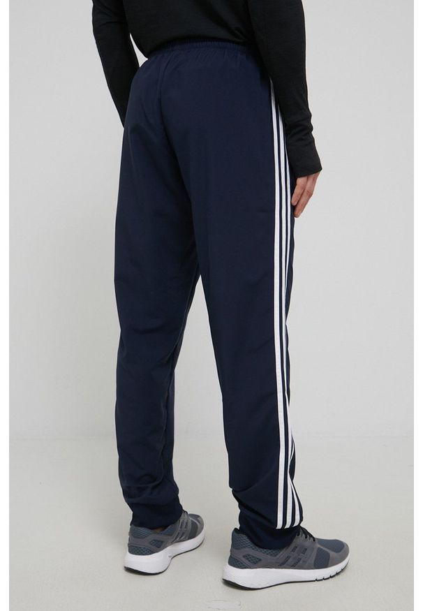 Adidas - adidas spodnie męskie kolor granatowy. Kolor: niebieski. Materiał: materiał. Wzór: aplikacja