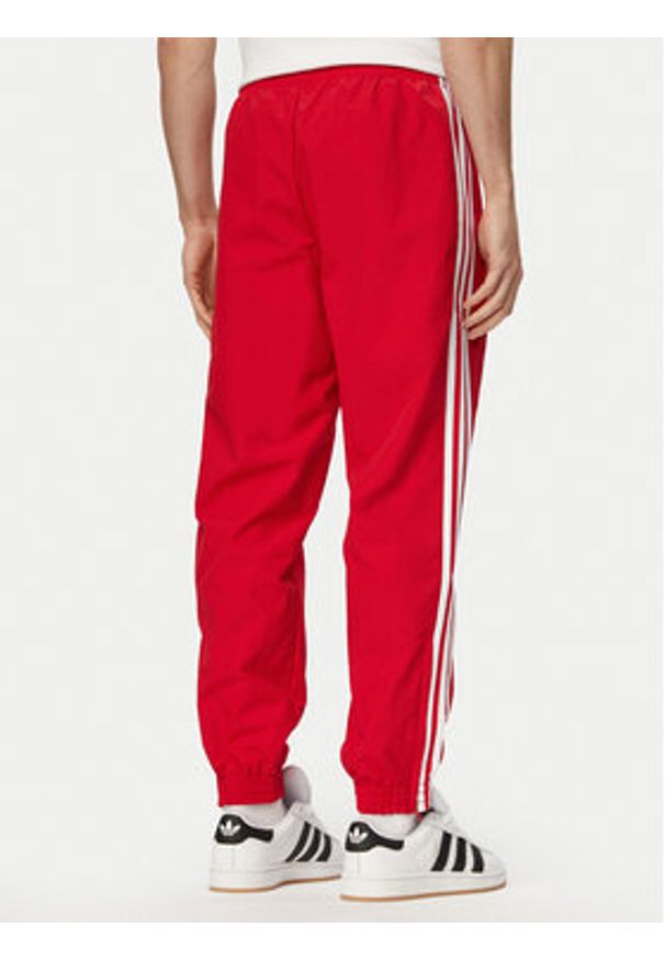Adidas - adidas Spodnie dresowe Firebird Woven KE1369 Czerwony Regular Fit. Kolor: czerwony. Materiał: syntetyk