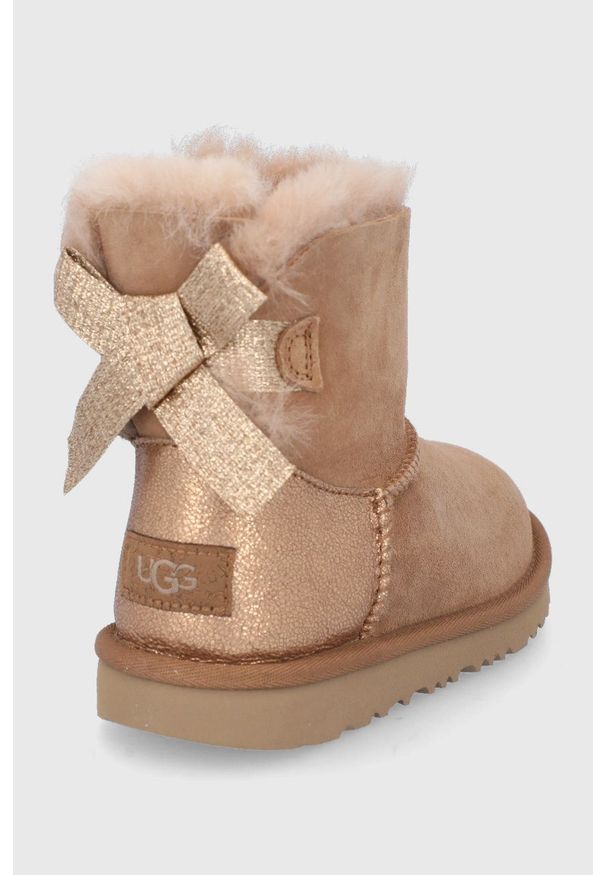 Ugg - UGG Śniegowce zamszowe dziecięce Mini Bailey Bow Glitz kolor brązowy. Nosek buta: okrągły. Kolor: brązowy. Materiał: zamsz. Szerokość cholewki: normalna