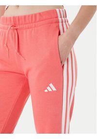Adidas - adidas Spodnie dresowe Essentials 3-Stripes KE4387 Koralowy Regular Fit. Kolor: pomarańczowy. Materiał: bawełna