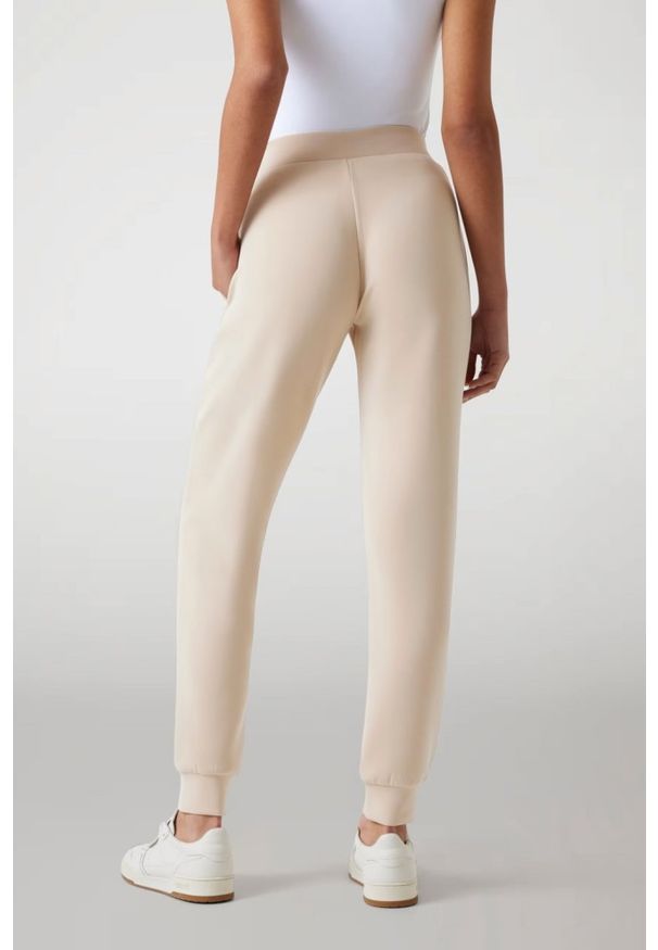 Guess - GUESS Spodnie damskie dresowe w kolorze taupe Olympe. Kolor: beżowy. Materiał: dresówka