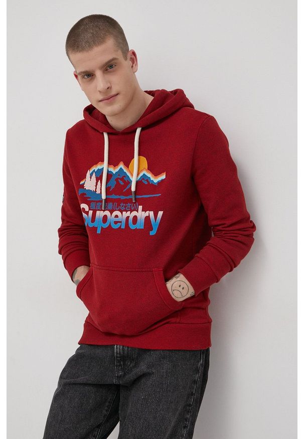 Superdry Bluza męska kolor czerwony z kapturem z nadrukiem. Typ kołnierza: kaptur. Kolor: czerwony. Materiał: dzianina. Wzór: nadruk