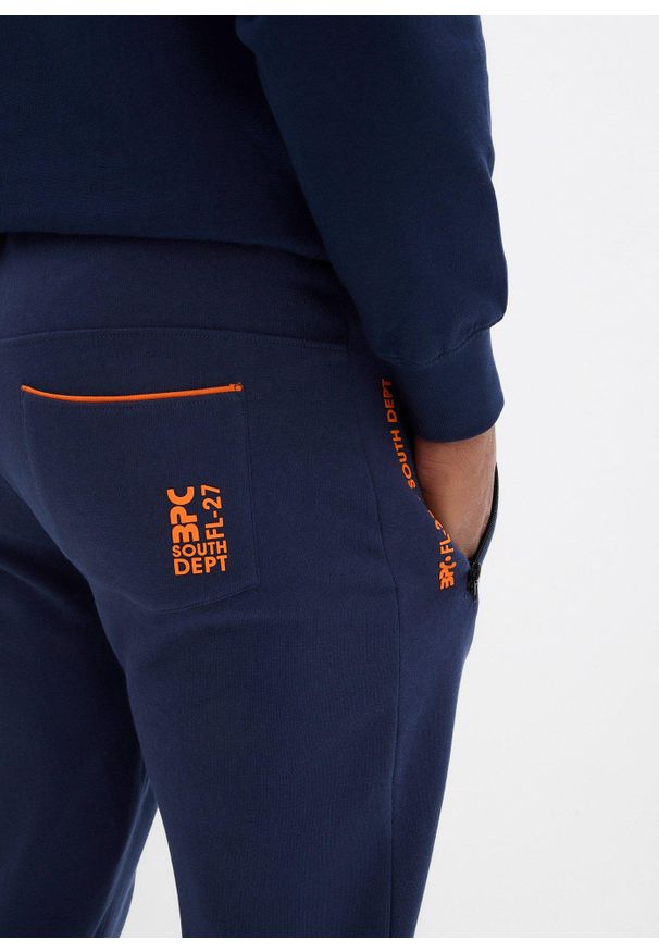 bonprix - Spodnie sportowe z praktycznymi kieszeniami zapinanymi na zamek. Kolor: niebieski. Styl: sportowy