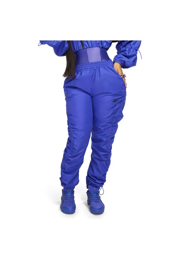 Damskie spodnie dresowe z tkaniny Reebok Cardi B. Kolor: fioletowy. Materiał: tkanina, dresówka. Sport: fitness