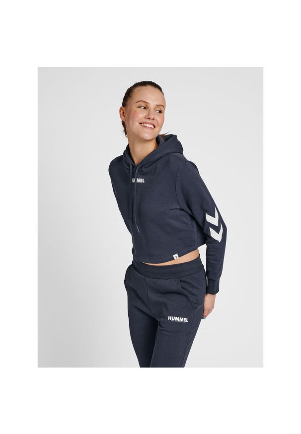 Damska bluza z kapturem crop top Hummel hmlLEGACY. Typ kołnierza: kaptur. Kolor: zielony, niebieski, wielokolorowy. Materiał: bawełna, tkanina. Wzór: nadruk. Sport: fitness