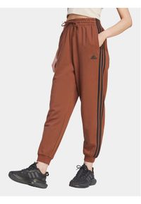 Adidas - adidas Spodnie dresowe Essentials 3-Stripes IL3451 Brązowy Loose Fit. Kolor: brązowy. Materiał: bawełna