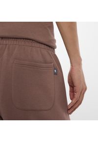 Spodnie męskie New Balance MP53508EAS – brązowe. Kolor: brązowy. Materiał: bawełna, dresówka, materiał, poliester. Wzór: aplikacja, napisy #5