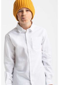 Volcano - Biała koszula chłopięca z podwijanymi rękawami K-LANGE JUNIOR. Kolor: biały. Materiał: jeans, bawełna, materiał. Długość rękawa: długi rękaw. Długość: długie. Wzór: aplikacja. Styl: klasyczny, wizytowy