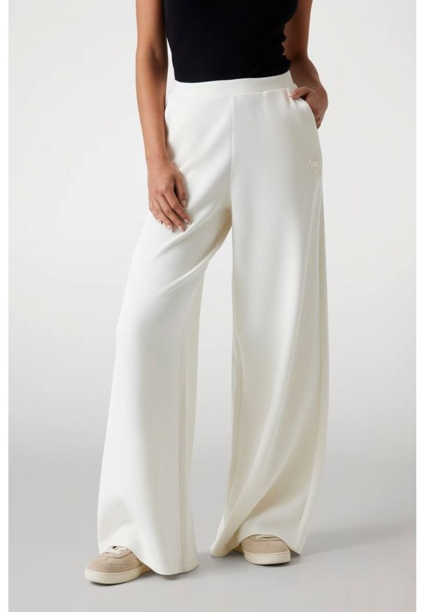 Guess - GUESS Spodnie damskie dresowe ecru Olympe Wide. Kolor: biały. Materiał: dresówka