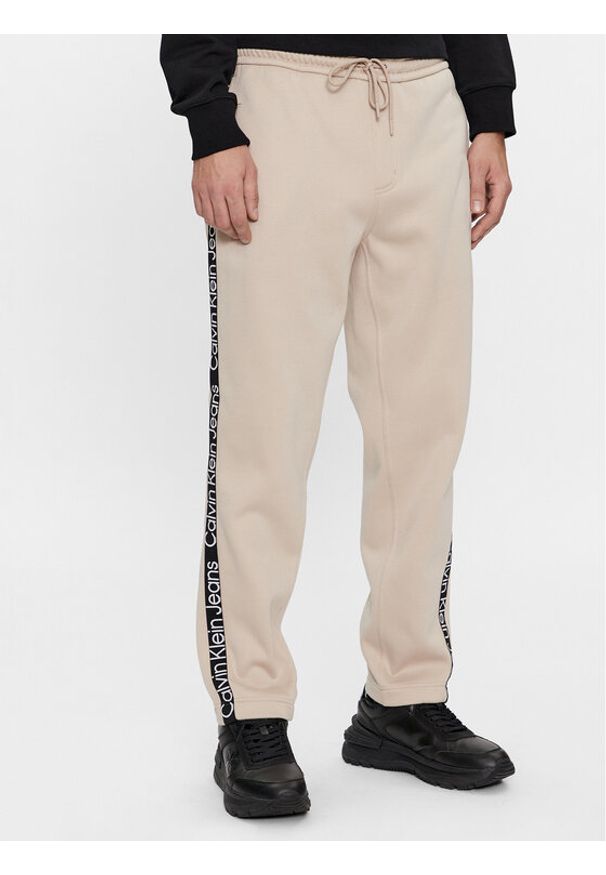Calvin Klein Jeans Spodnie dresowe Logo Tape J30J324376 Beżowy Relaxed Fit. Kolor: beżowy. Materiał: syntetyk