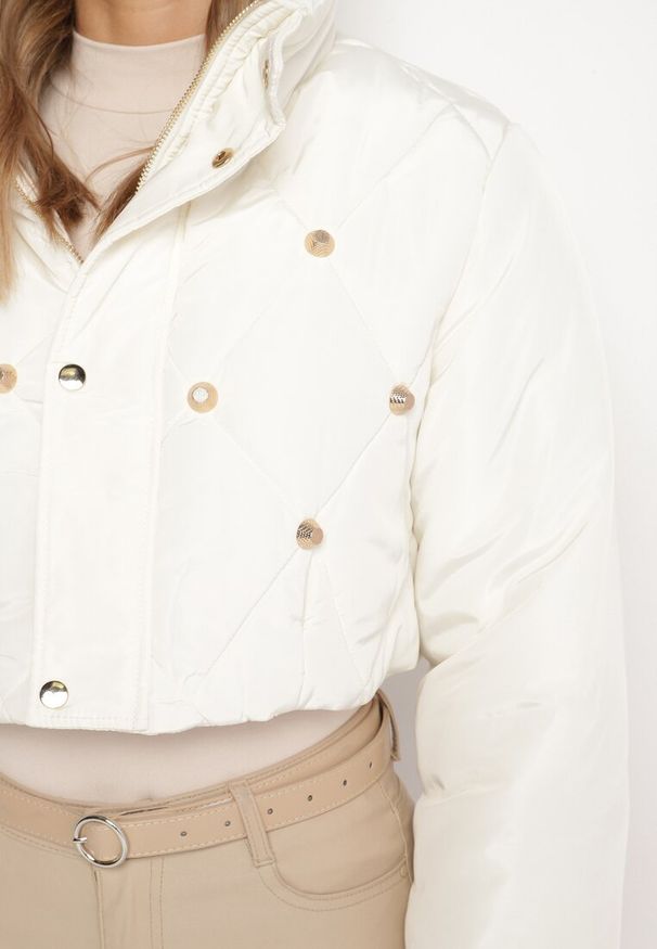 Born2be - Jasnobeżowa Pikowana Kurtka Puffer o Krótkim Kroju ze Stójką Zdobiona Napami Zinnavira. Okazja: na co dzień. Typ kołnierza: kołnierzyk stójkowy. Kolor: beżowy. Materiał: jeans, materiał. Długość: krótkie. Wzór: aplikacja. Styl: casual, elegancki