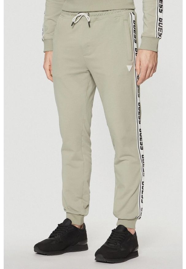 Guess - GUESS Zielone męskie spodnie dresowe z lampasami New Arlo, Rozmiar L. Kolor: zielony. Materiał: dresówka