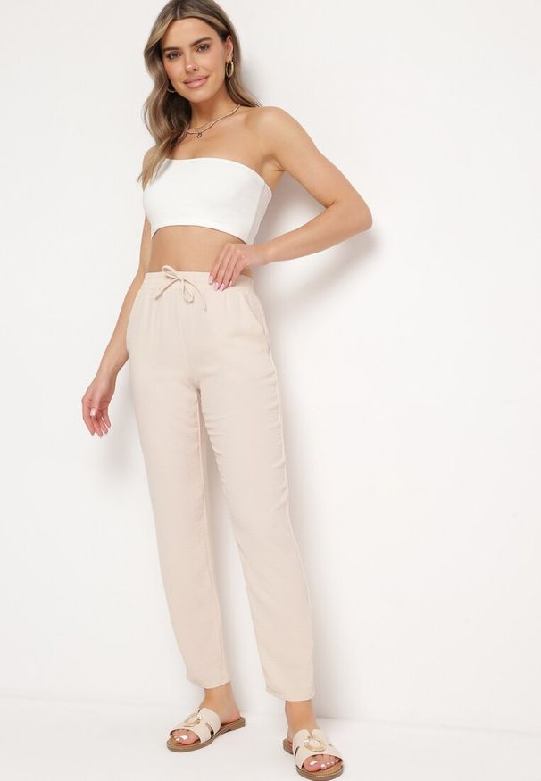 Born2be - Jasnobeżowe Spodnie Wiązane Troczkiem w Pasie ze Zwężającymi się Nogawkami Starila. Okazja: na co dzień. Kolor: beżowy. Materiał: len. Styl: casual, elegancki, wakacyjny
