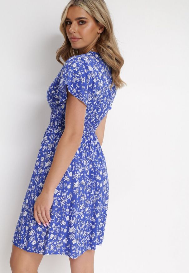 Born2be - Granatowa Kwiecista Sukienka Mini z Wiskozy z Marszczoną Gumką w Pasie Catela. Kolor: niebieski. Materiał: wiskoza. Długość rękawa: krótki rękaw. Wzór: kwiaty. Sezon: wiosna, lato. Typ sukienki: rozkloszowane, kopertowe. Długość: mini