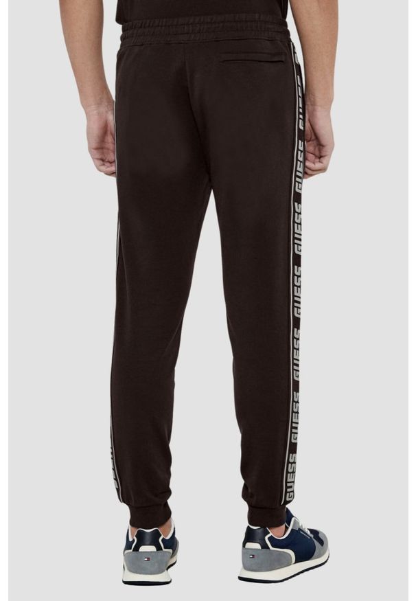 Guess - GUESS Brązowe męskie spodnie dresowe z lampasami New Arlo, Rozmiar XXL. Kolor: brązowy. Materiał: dresówka