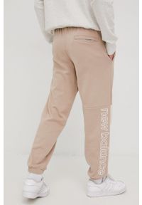 New Balance spodnie dresowe bawełniane męskie kolor beżowy z nadrukiem. Kolor: beżowy. Materiał: dresówka, bawełna. Wzór: nadruk