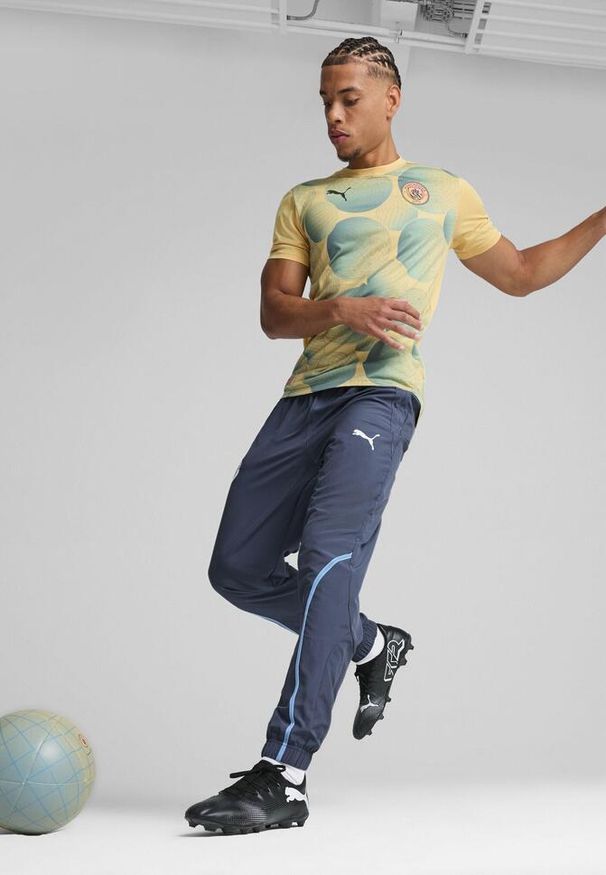 Puma - Męska koszulka przedmeczowa z krótkim rękawem Manchester City PUMA. Kolor: wielokolorowy, niebieski, żółty. Długość rękawa: krótki rękaw. Długość: krótkie