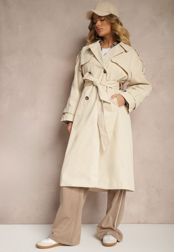 Renee - Beżowy Płaszcz Trencz o Dwurzędowym Kroju z Rozcięciem i Klapą Wiązany w Talii Valezi. Okazja: na co dzień, do pracy, na spacer. Kolor: beżowy. Materiał: dzianina, skóra, jeans. Długość rękawa: długi rękaw. Długość: długie. Wzór: aplikacja. Styl: casual, elegancki