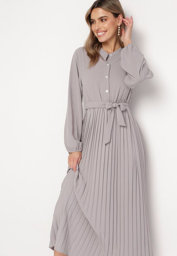 Born2be - Ciemnoszara Rozkloszowana Sukienka Maxi z Plisowanym Dołem i Wiązanym Paskiem Nollira. Kolor: szary. Materiał: materiał. Długość rękawa: długi rękaw. Typ sukienki: plisowane. Styl: elegancki. Długość: maxi
