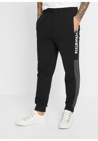bonprix - Spodnie sportowe z poliestru z recyklingu. Kolor: czarny. Materiał: poliester. Wzór: napisy. Styl: sportowy #1