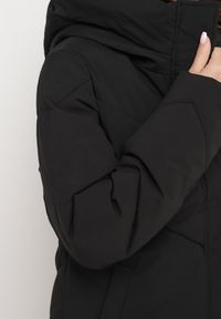 Born2be - Czarna Kurtka Pikowana o Długim Fasonie z Nieodpinanym Kapturem i Kieszeniami Nerilani. Okazja: na co dzień, na spacer. Kolor: czarny. Materiał: skóra. Długość: długie. Sezon: zima. Styl: casual, elegancki #6