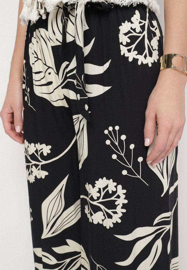 Born2be - Czarne Spodnie w Kwiaty o Szerokim Kroju z Gumką i Paskiem Eledina. Okazja: na co dzień. Kolor: czarny. Wzór: kwiaty. Styl: elegancki, casual