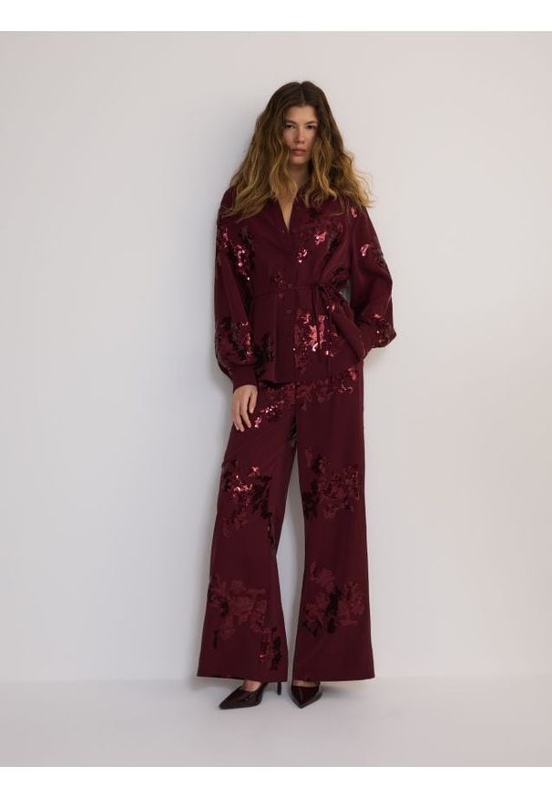 Reserved - Luźne spodnie z cekinowymi aplikacjami - burgundowy. Kolor: czerwony. Materiał: tkanina, satyna. Wzór: aplikacja