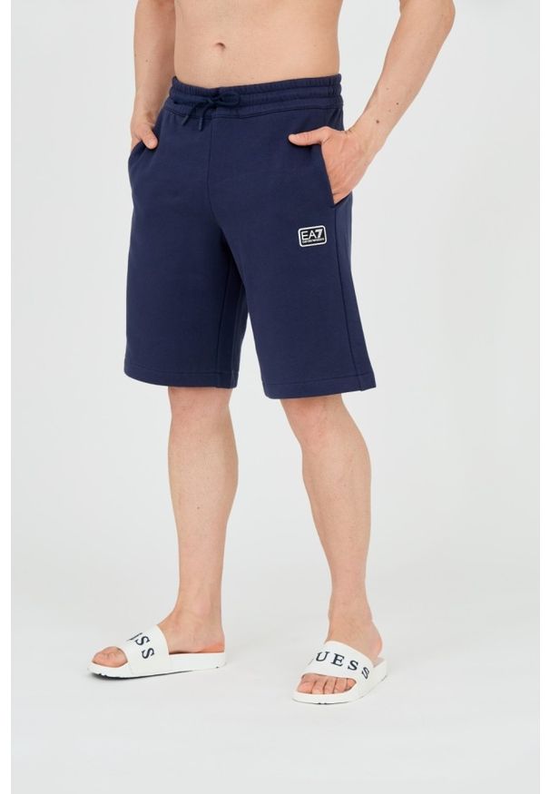 EA7 Emporio Armani - EA7 Męskie granatowe shorty z naszywką. Kolor: niebieski. Materiał: bawełna. Długość: krótkie. Wzór: aplikacja