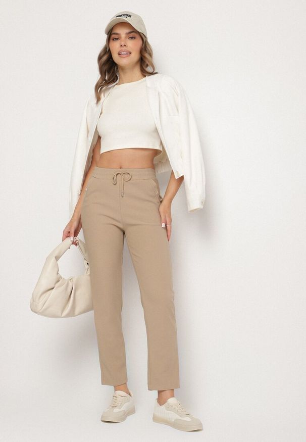 Born2be - Jasnobeżowe Szerokie Spodnie z Wiązaniem i Metalicznymi Aplikacjami Mairae. Okazja: na co dzień. Kolor: beżowy. Wzór: aplikacja. Styl: casual, elegancki