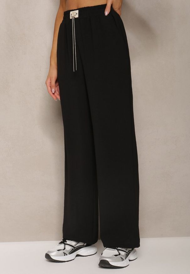 Renee - Czarne Spodnie Luźne o Szerokich Nogawkach z Łańcuszkiem zamiast Troczka Ostaria. Okazja: na spotkanie biznesowe, do pracy. Stan: podwyższony. Kolor: czarny. Wzór: aplikacja. Styl: biznesowy