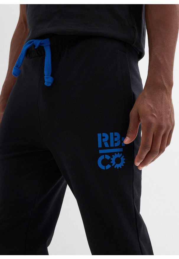 bonprix - Spodnie sportowe z kontrastowymi elementami. Kolor: czarny. Materiał: poliester, dresówka. Wzór: nadruk. Styl: sportowy