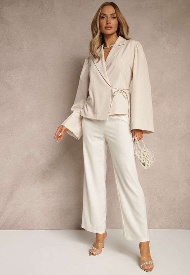 Renee - Jasnobeżowa Marynarka z Rozszerzanymi Rękawami Zdobiona Wiązaniem z Boku Sanivera. Okazja: do pracy, na spotkanie biznesowe. Kolor: beżowy. Wzór: aplikacja. Styl: biznesowy, klasyczny, elegancki