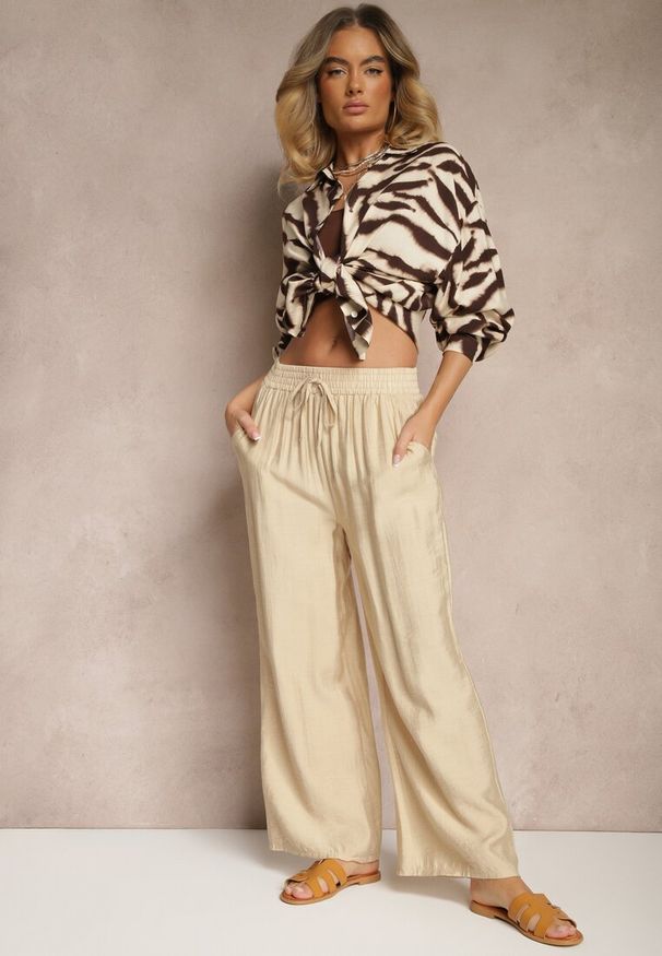 Renee - Beżowe Spodnie Typu Palazzo o Szerokim Kroju High Waist Ozdobione Wiązaniem Yaslevia. Okazja: na co dzień. Stan: podwyższony. Kolor: beżowy. Wzór: aplikacja. Styl: elegancki, casual