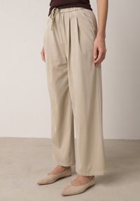 Born2be - Beżowe Szerokie Spodnie z Bawełną Wiskozą Gumką w Pasie i Sznurkiem Iridara. Okazja: na co dzień. Stan: podwyższony. Kolor: beżowy. Materiał: wiskoza, bawełna. Styl: casual, elegancki, klasyczny #1