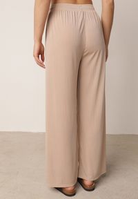 Born2be - Beżowe Spodnie z Wysokim Stanem i Szerokimi Nogawkami Zdobione Guzikiem Kelesh. Okazja: do pracy, na co dzień. Stan: podwyższony. Kolekcja: plus size. Kolor: beżowy. Materiał: tkanina, prążkowany. Długość: długie. Wzór: aplikacja. Styl: elegancki, casual #5