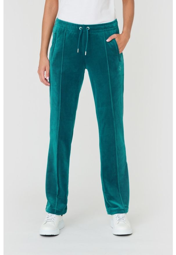 Juicy Couture - JUICY COUTURE Turkusowe spodnie Tina. Kolor: niebieski. Materiał: poliester. Wzór: aplikacja