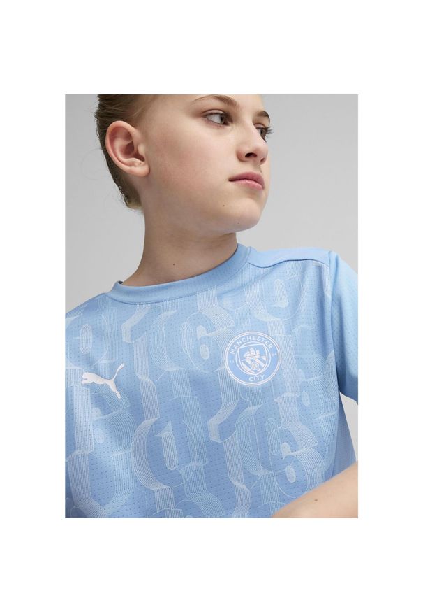 Puma - Młodzieżowa koszulka przedmeczowa z krótkim rękawem Manchester City PUMA. Kolor: biały, wielokolorowy, niebieski. Długość rękawa: krótki rękaw. Długość: krótkie