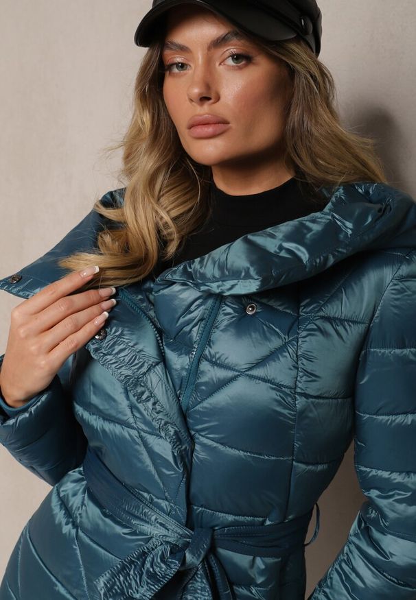 Renee - Niebieska Kurtka Pikowana o Długim Kroju z Kapturem Ozdobiona Wiązaniem w Talii Anselith. Typ kołnierza: kaptur. Kolor: niebieski. Materiał: jeans. Długość: długie. Wzór: aplikacja. Styl: elegancki