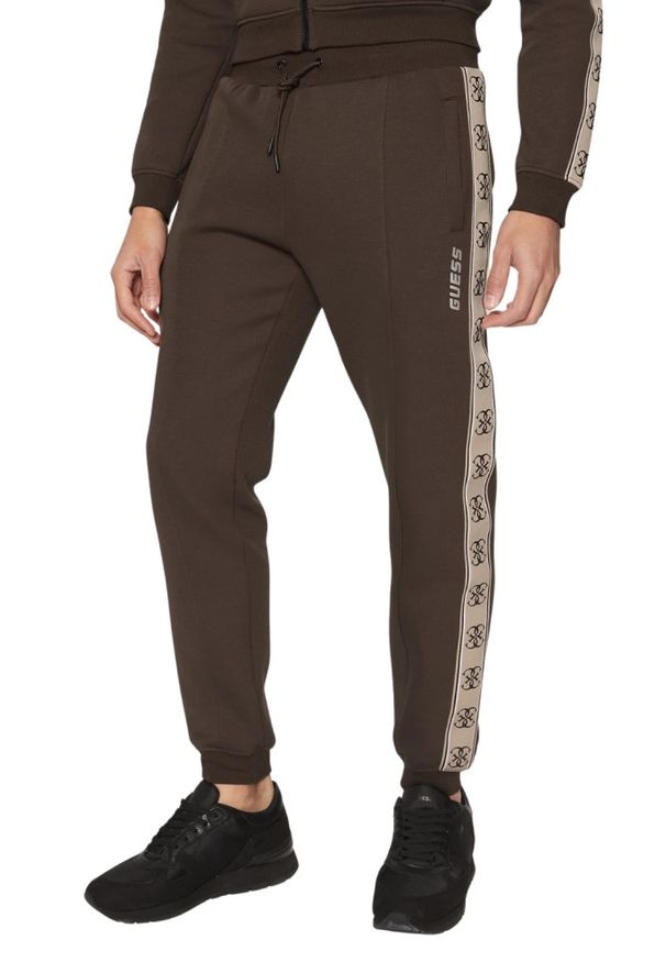 Guess - GUESS Brązowe męskie spodnie dresowe z lampasami Mickey, Rozmiar S. Kolor: brązowy. Materiał: dresówka