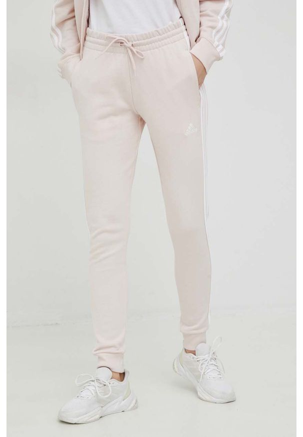 Adidas - adidas spodnie dresowe kolor różowy z aplikacją. Kolor: różowy. Materiał: dresówka. Wzór: aplikacja