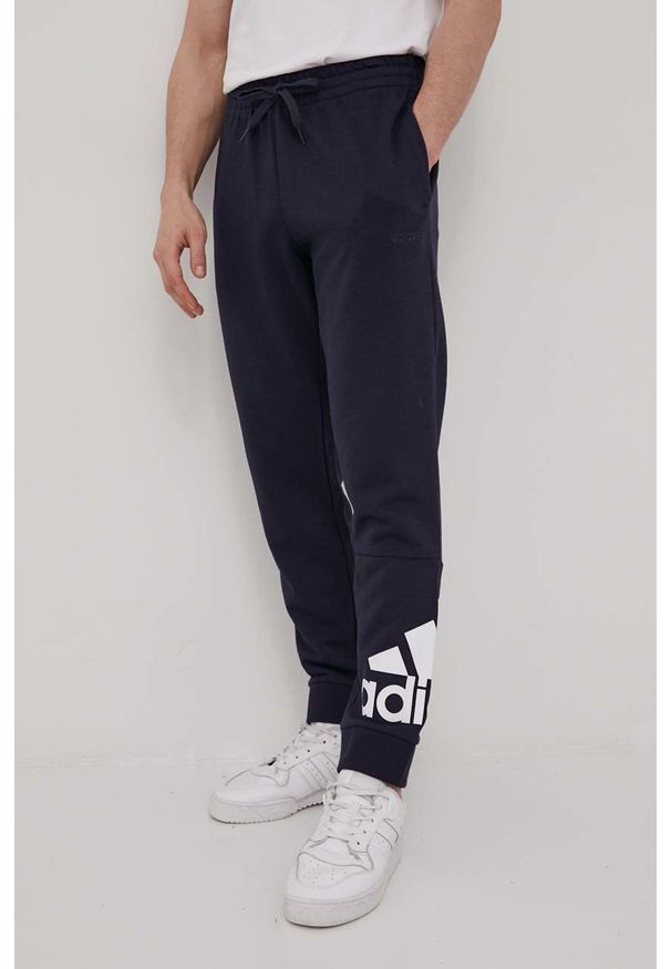Adidas - adidas spodnie męskie kolor granatowy z nadrukiem. Kolor: niebieski. Materiał: materiał, bawełna, dzianina. Wzór: nadruk