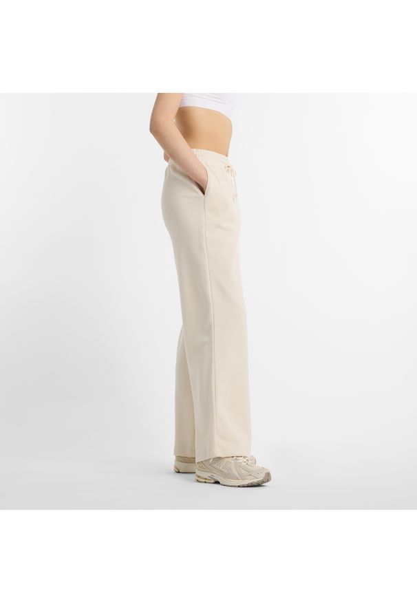 Spodnie damskie New Balance WP51503LIN – beżowe. Kolor: beżowy. Materiał: poliester, bawełna. Wzór: aplikacja, haft