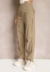 Renee - Ciemnobeżowe Szerokie Spodnie High Waist w Stylu Bojówek Wykończone Gumką w Talii Ellcara. Okazja: na co dzień. Stan: podwyższony. Kolor: beżowy. Materiał: satyna. Wzór: moro. Styl: elegancki, sportowy, militarny, wizytowy, casual #5