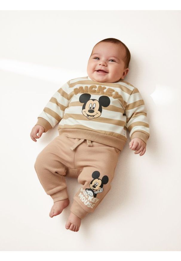 Sinsay - Spodnie dresowe Mickey Mouse - beżowy. Kolor: beżowy. Materiał: dresówka. Wzór: motyw z bajki