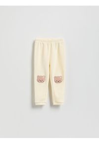 Reserved - Prążkowane legginsy z naszywką - złamana biel. Materiał: prążkowany. Wzór: aplikacja