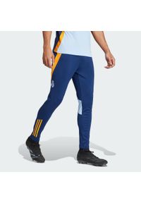 Adidas - Spodnie treningowe Real Madrid 2024/25. Kolor: pomarańczowy, niebieski, wielokolorowy. Materiał: poliester. Sport: piłka nożna