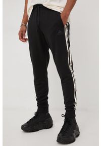 Adidas - adidas spodnie dresowe męskie kolor czarny z aplikacją. Kolor: czarny. Materiał: dresówka. Wzór: aplikacja