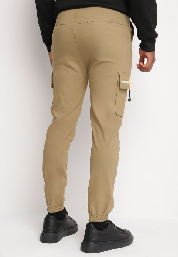 Born2be - Ciemnobeżowe Spodnie Cargo z Bawełną Ozdobione Napisem i Gumką w Pasie Tarionna. Okazja: na co dzień. Kolor: beżowy. Materiał: bawełna. Wzór: aplikacja, napisy. Styl: casual