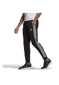 Adidas - Spodnie adidas Essentials Fleece Tapered Cuff 3-Stripes Pants GK8821 - czarne. Kolor: czarny. Materiał: dresówka