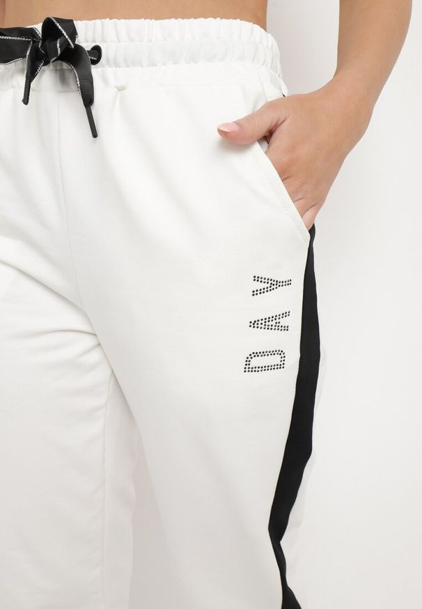 Born2be - Białe Spodnie Dresowe z Lampasem i Ozdobnym Napisem Adkarsa. Okazja: na co dzień. Kolor: biały. Materiał: dresówka. Wzór: napisy. Styl: casual